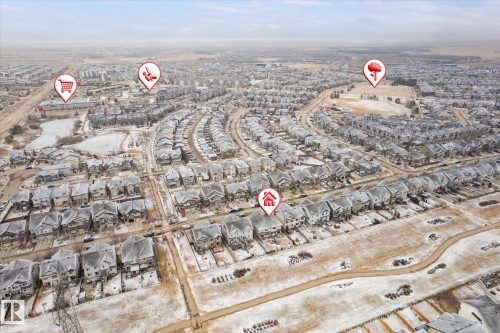 Aerial perspective showcasing a residential neighborhood with uniformly designed homes featuring snow-dusted roofs, extensive street networks, and open land areas - 1668 Chapman Way Sw, Edmonton, AB - Outdoor With View