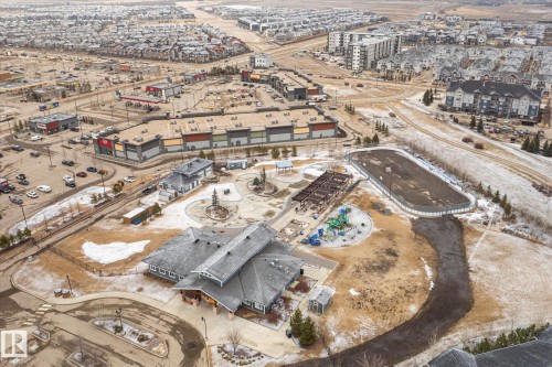 Expansive aerial perspective showcasing a community park with a central building, playground, and an outdoor rink - 1668 Chapman Way Sw, Edmonton, AB - Outdoor With View