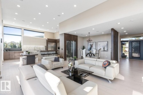 Main Floor Living Space featuring Floor to Ceiling Windows with Motorized Hunter Douglas Blinds, Opti-Myst Fireplace, and Custom Entertainment Unit. - 5536 Chegwin Point(E), Edmonton, AB - Indoor Photo Showing Living Room