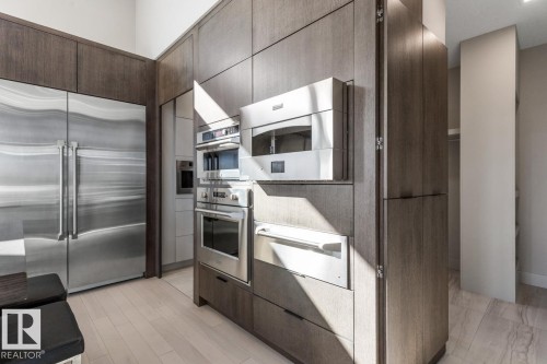 Stunning Kitchen featuring floor to ceiling windows with remote blinds, Gas Stove Top, Pizza Oven, Microwave Convection Oven, Oversized Refrigerator, Granite Counters, and Two Tone Cabinets. - 5536 Chegwin Point(E), Edmonton, AB - Indoor Photo Showing Kitchen
