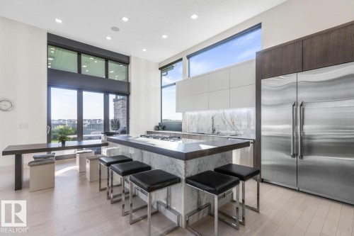 Stunning Kitchen featuring floor to ceiling windows with remote blinds, Gas Stove Top, Pizza Oven, Microwave Convection Oven, Oversized Refrigerator, Granite Counters, and Two Tone Cabinets. - 5536 Chegwin Point(E), Edmonton, AB - Indoor Photo Showing Dining Room