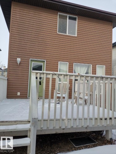 The property features a brown-sided exterior with a white deck and railings, accessible via exterior stairs - 115 Keystone Lane, Leduc, AB - Outdoor With Exterior