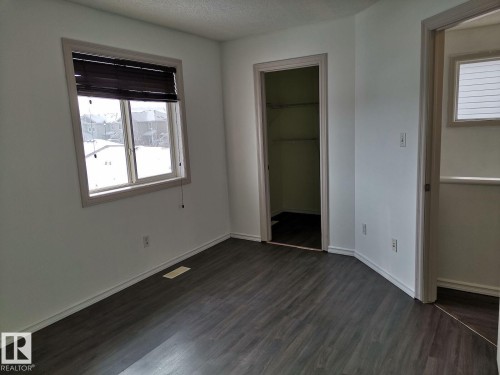 This room features dark-toned flooring, white walls, and a window with blinds - 115 Keystone Lane, Leduc, AB - Indoor Photo Showing Other Room