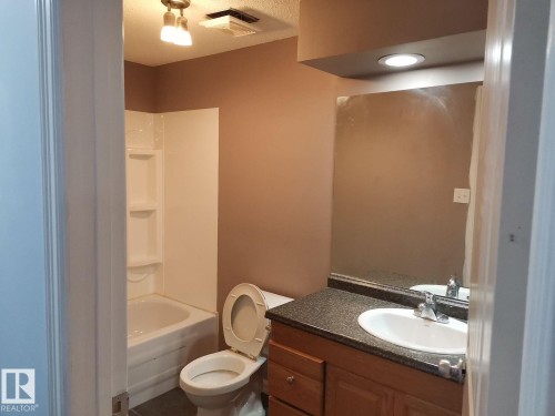 Bathroom featuring a vanity with an integrated sink, a mirror, and a bathtub with a shower - 115 Keystone Lane, Leduc, AB - Indoor Photo Showing Bathroom