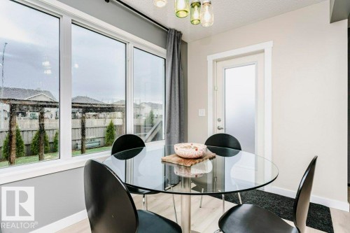 Dining area featuring a large window array, light wood-finish flooring, a contemporary glass door, and a multi-pendant light fixture - 42 Santana Crescent, Fort Saskatchewan, AB - Indoor Photo Showing Dining Room