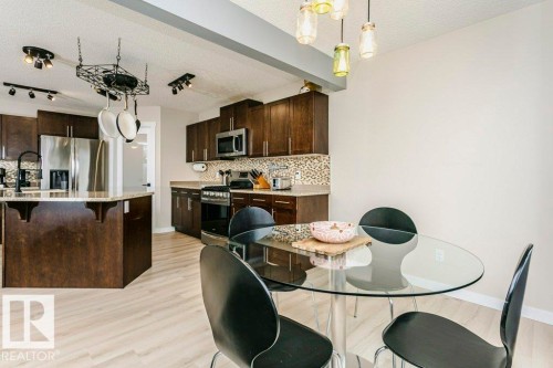 Open concept kitchen with wood-finish flooring, dark wood cabinetry, and stainless steel appliances - 42 Santana Crescent, Fort Saskatchewan, AB - Indoor