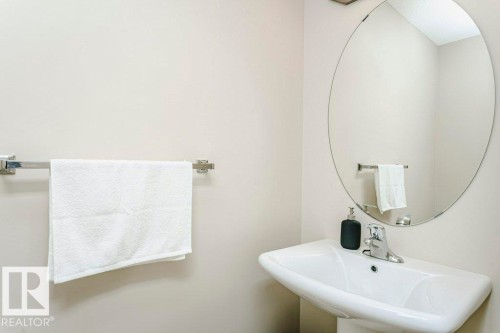 Pedestal sink with chrome faucet, complemented by a round frameless mirror - 42 Santana Crescent, Fort Saskatchewan, AB - Indoor Photo Showing Bathroom