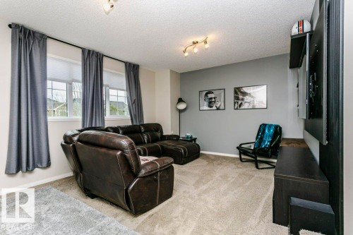 Living area featuring neutral-tone carpeting, a light gray accent wall, and a track lighting fixture - 42 Santana Crescent, Fort Saskatchewan, AB - Indoor