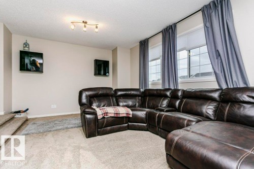 Carpeted living area featuring track lighting, multiple windows with grid patterns, and neutral wall tones - 42 Santana Crescent, Fort Saskatchewan, AB - Indoor Photo Showing Living Room