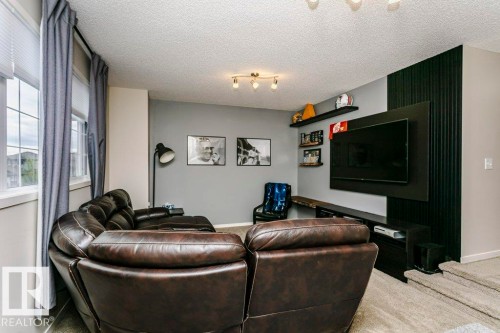 Living area featuring textured gray walls, track lighting, an integrated entertainment center with a slatted accent wall, and a multi-panel window with white trim - 42 Santana Crescent, Fort Saskatchewan, AB - Indoor