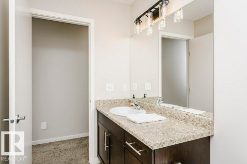 Bathroom vanity featuring a light speckled countertop, undermount sink, and dark wood-finish cabinetry with brushed nickel hardware - 42 Santana Crescent, Fort Saskatchewan, AB - Indoor Photo Showing Bathroom