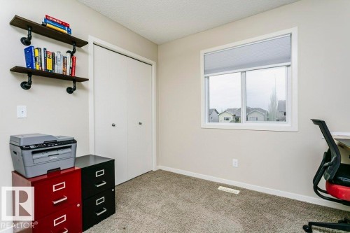 Interior room featuring neutral wall paint, textured carpeting, a white-framed window with blinds, and white bi-fold closet doors - 42 Santana Crescent, Fort Saskatchewan, AB - Indoor Photo Showing Other Room