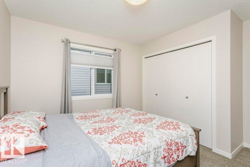 Bedroom featuring neutral wall paint, textured ceiling, a window with blinds and drapes, and a white bi-fold closet - 42 Santana Crescent, Fort Saskatchewan, AB - Indoor Photo Showing Bedroom