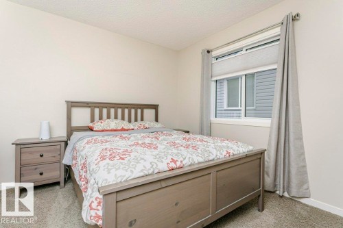 Bedroom featuring neutral wall paint, textured carpet flooring, a window with horizontal blinds, and a curtain rod with drapes - 42 Santana Crescent, Fort Saskatchewan, AB - Indoor Photo Showing Bedroom