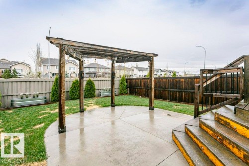 Backyard featuring a concrete patio with an overhead pergola, green lawn, and wood fencing - 42 Santana Crescent, Fort Saskatchewan, AB - Outdoor