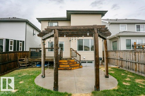 Backyard featuring a concrete patio with a wooden pergola, a multi-level wooden deck with stairs, a privacy fence, and a manicured lawn - 42 Santana Crescent, Fort Saskatchewan, AB - Outdoor