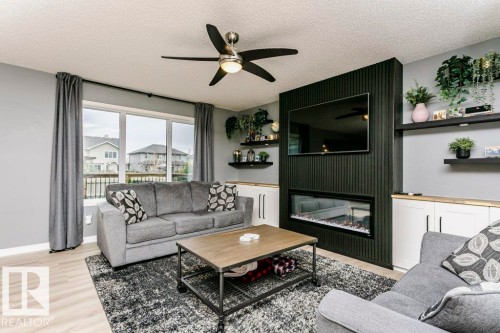 Living area featuring light wood-finish flooring and a ceiling fan with integrated lighting - 42 Santana Crescent, Fort Saskatchewan, AB - Indoor Photo Showing Living Room With Fireplace