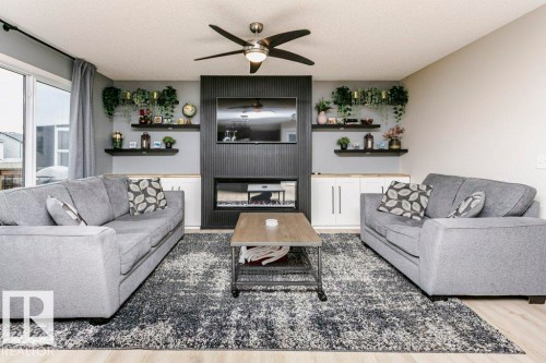 Living area featuring a textured accent wall with an integrated electric fireplace - 42 Santana Crescent, Fort Saskatchewan, AB - Indoor Photo Showing Living Room With Fireplace