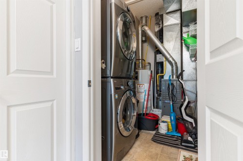 Utility area featuring a stacked washer and dryer, water heater, and furnace - 73 3040 Spence Wynd, Edmonton, AB - Indoor Photo Showing Laundry Room