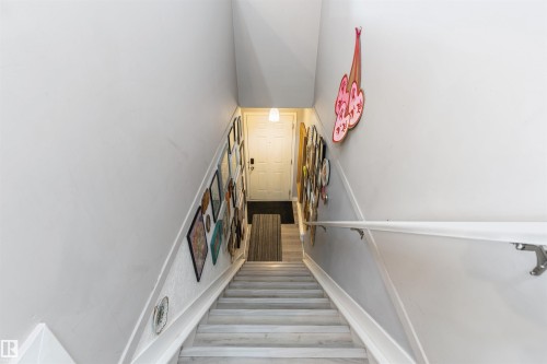 Staircase featuring light-toned wood-finish flooring, white risers, and a white handrail with metal brackets - 73 3040 Spence Wynd, Edmonton, AB - Indoor Photo Showing Other Room