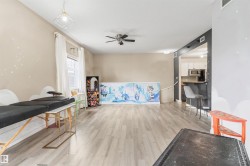Open-concept living area featuring wood-finish flooring, a ceiling fan, and a pass-through window to the kitchen - 