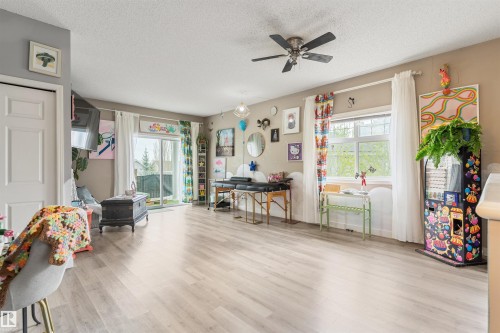 Spacious room featuring light wood-finish flooring, a ceiling fan with integrated lighting, and neutral wall tones - 73 3040 Spence Wynd, Edmonton, AB - Indoor
