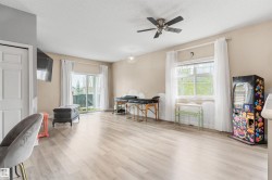 Spacious room featuring wood-finish flooring, a ceiling fan, and light-toned walls - 