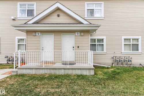 Two-story duplex with light beige horizontal siding, white trim windows, and a central gable accent - 73 3040 Spence Wynd, Edmonton, AB - Outdoor
