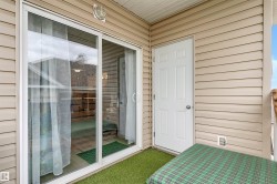 Exterior balcony featuring vinyl siding, a white sliding glass door, a white paneled exterior door, and a textured ceiling - 