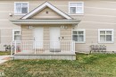 Two-story duplex with light beige horizontal siding, white trim windows, and a central gable accent - 73 3040 Spence Wynd, Edmonton, AB  - Outdoor 