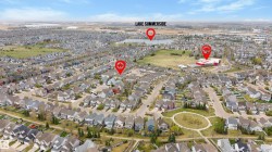 Aerial perspective of a developed residential neighborhood featuring numerous single-family homes and a central green space - 