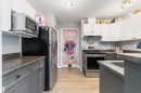 Kitchen featuring wood-finish flooring, stainless steel appliances, white upper cabinetry, and contrasting gray lower cabinetry - 73 3040 Spence Wynd, Edmonton, AB  - Indoor Photo Showing Kitchen With Stainless Steel Kitchen 
