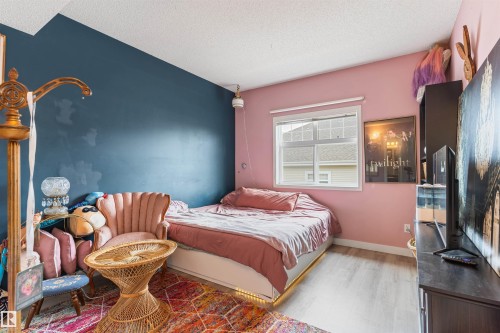 Bedroom featuring light wood-finish flooring, a white window frame, and diverse wall colors - 73 3040 Spence Wynd, Edmonton, AB - Indoor Photo Showing Bedroom