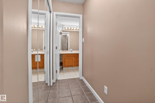 Hallway featuring neutral wall paint, white trim, and square floor tiles - 104 9760 174 Street, Edmonton, AB - Indoor Photo Showing Other Room