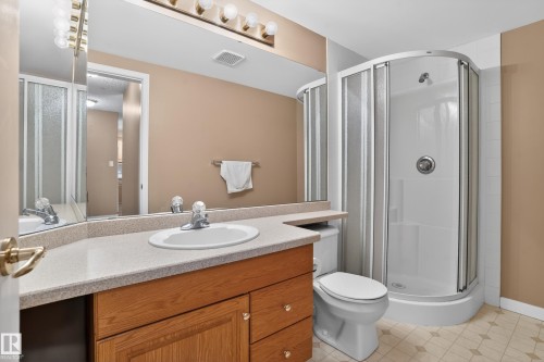 Bathroom featuring a corner shower enclosure, light wood-finish vanity with an integrated sink, and a light-toned countertop - 104 9760 174 Street, Edmonton, AB - Indoor Photo Showing Bathroom