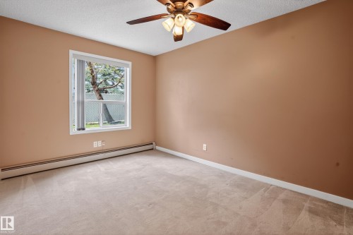 Carpeted room featuring a white-framed window, baseboard heating, and a ceiling fan with integrated lighting - 104 9760 174 Street, Edmonton, AB - Indoor Photo Showing Other Room