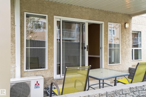 Covered patio area featuring stucco exterior, sliding glass door, and exterior sconce lighting - 104 9760 174 Street, Edmonton, AB - Outdoor With Deck Patio Veranda With Exterior