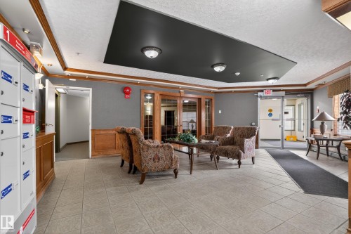 Lobby area featuring neutral-toned tile flooring and wood-paneled accents - 104 9760 174 Street, Edmonton, AB - Indoor Photo Showing Other Room