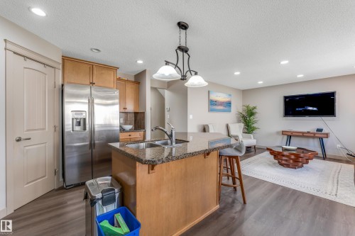 The kitchen features a functional island with a sink and a stainless steel refrigerator - 463 Tamarack Green, Edmonton, AB - Indoor Photo Showing Kitchen With Double Sink