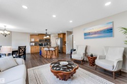 Open-concept living space with recessed lighting, hard surface flooring, and a kitchen featuring wooden cabinetry and a breakfast bar with seating - 