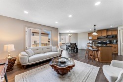 The open concept living area features recessed lighting, dark wood-style flooring, and a sliding glass door providing natural light - 