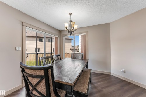 The property features a dining area with dark wood flooring and light-colored walls - 463 Tamarack Green, Edmonton, AB - Indoor Photo Showing Dining Room