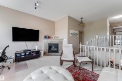 Living area featuring a fireplace with a tiled surround, light-colored carpet, and a white balustrade - 