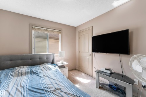 This room features a window with blinds, carpeted flooring, and a paneled door - 463 Tamarack Green, Edmonton, AB - Indoor Photo Showing Bedroom