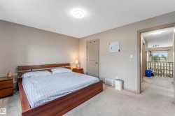 Carpeted bedroom with neutral walls, featuring a wooden bed frame and two matching wooden nightstands - 