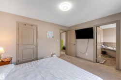 This bedroom features neutral-toned walls, a ceiling-mounted light fixture, and carpeted floors - 