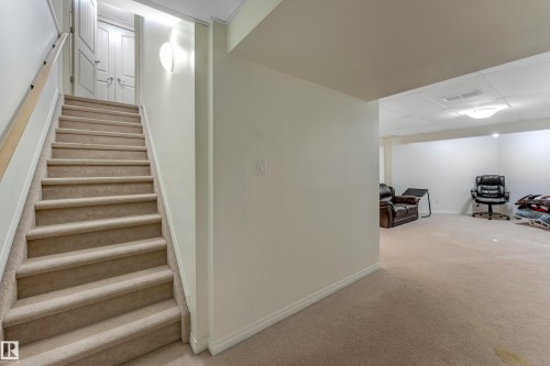 The property features a staircase with carpeted steps and a wooden handrail, leading to a landing with two white doors - 463 Tamarack Green, Edmonton, AB - Indoor Photo Showing Other Room