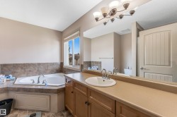 Bathroom featuring a built-in corner tub with tiled surround, a vanity with a counter and an integrated sink, and a large mirror with overhead lighting - 