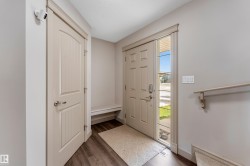 Entryway featuring a front door with side lite, light grey walls, and dark flooring - 