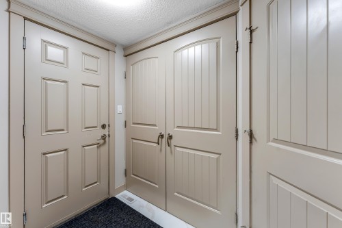 Entryway featuring a panel door, double bifold doors with vertical planking, and crown molding - 463 Tamarack Green, Edmonton, AB - Indoor Photo Showing Other Room